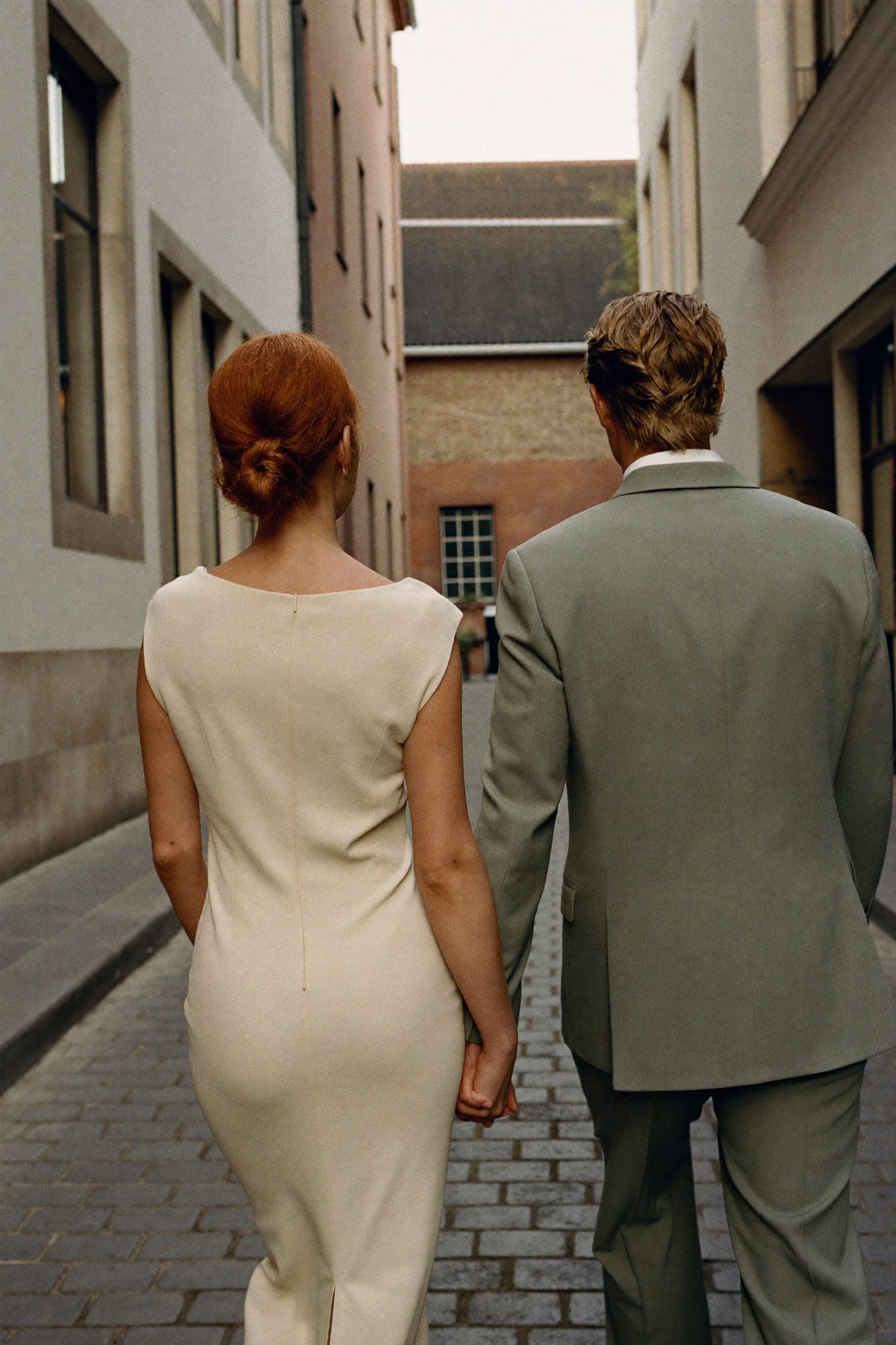 Amber en Ward wandelen hand in hand door een historisch straatje, gefotografeerd op afstand